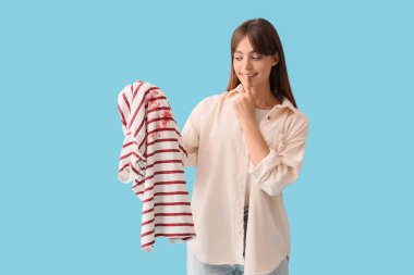 Mavi arka planda lekeli elbiseli genç bir kadın.