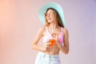 Hafif arka planda aperol sprey kokteyli olan güneş gözlüklü genç bir kadın.