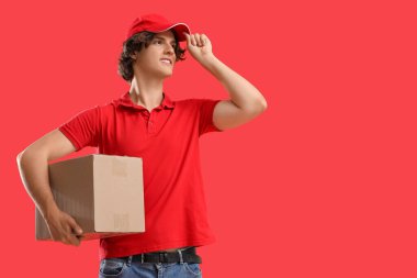 Kırmızı arka planda karton kutulu erkek kurye