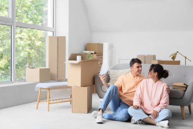 Genç çift taşınma gününde odada oturuyor.