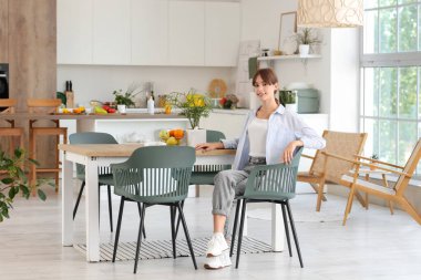 Genç bayan yemek odasında masada oturuyor.