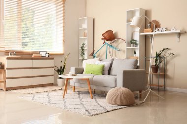 Koltuk, çekmeceler, sehpa, raf üniteleri ve oturma odasındaki bej duvarın yanında bisiklet.