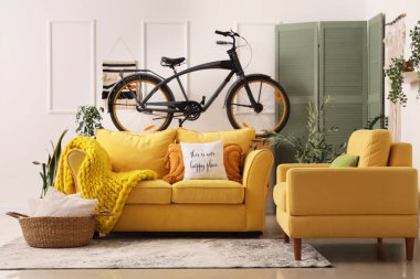 Oturma odasının iç tarafında rahat bir kanepe, koltuk ve bisiklet.