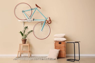 Rafta bisiklet, yastıklı sepet ve odada çiçek.