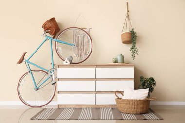 Çekmeceler ve bisiklet, odada bej duvarın yanında.