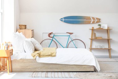 Büyük yataklı yatak odası, raf ünitesi, bisiklet ve sörf tahtası.