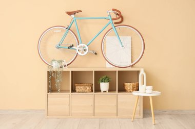 Raflama ünitesi, kahve masası ve bisiklet odada bej duvarın yanında.