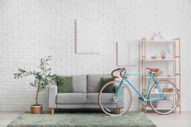 Koltuk, raf ünitesi, dekoratif ağaç ve bisiklet oturma odasının içinde.