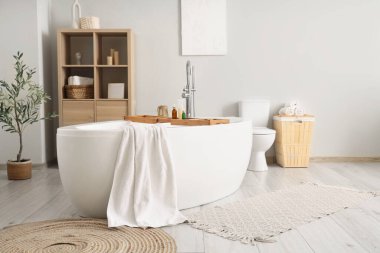 Banyonun içinde havlu, klozet ve raf ünitesi olan küvet.