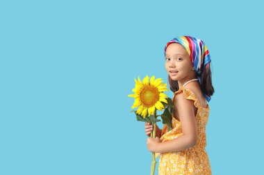 Mavi arka planda güzel bir ayçiçeği olan tatlı bir Asyalı kız.