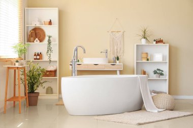 Banyonun içinde havlu, lavabo ve raf üniteleri olan küvet.