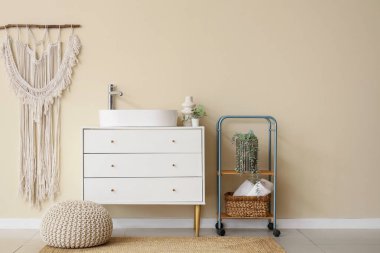 Göğüs çekmecesi, lavabo ve pouf.