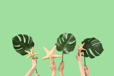 Yeşil arka planda deniz yıldızı ve canavar yapraklı kadın eller. Seyahat kavramı