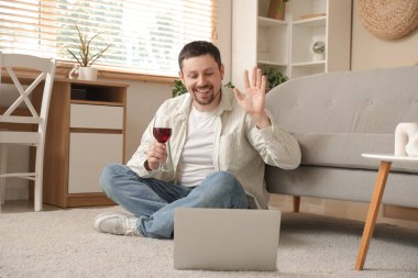 Evde internetten randevusu olan, bir bardak şarap ve dizüstü bilgisayarlı yakışıklı bir adam.