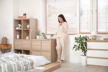 Bilgisayarlı genç Asyalı kadın yatak odasında online randevusu var.