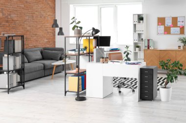 Çalışma yeri, raf üniteleri ve kanepesi olan modern ofis.