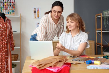 Atölyede dizüstü bilgisayarla çalışan kadın terziler.