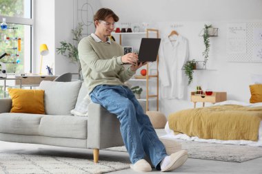 Güvenlik gözlüklü erkek öğrenci evde dizüstü bilgisayarla kimya okuyor.