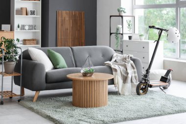 Oturma odasının içinde elektrikli scooter, kanepe ve masa var.