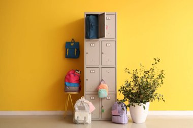 Sarı duvarın yanında okul çantalı bir dolap.