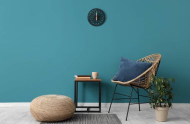 Koltuk, saksı, kahve masası ve mavi duvarın yanındaki puf.