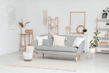 Interior of light living room with grey sofa and shelf units clipart