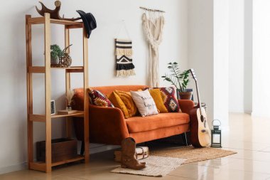 Oturma odasının içinde kanepe, kovboy şapkası ve çizmeleri var.