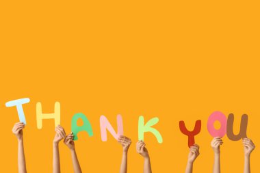 Sarı arkaplandaki kağıttan yapılmış teşekkür mesajı tutan kadın elleri.