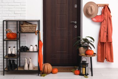 Koridorun içinde kapısı, raf ünitesi ve sonbahar dekoru var.