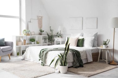 Yatak odasının içinde raf ünitesi, yeşil bitkiler ve lambalar var.