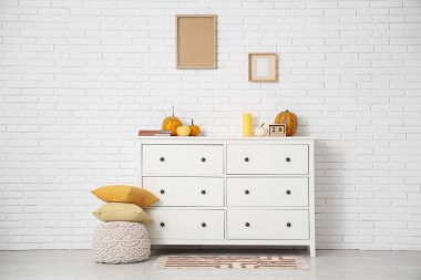 Yastıklı puf ve beyaz tuğla duvarın yanındaki çekmeceler.