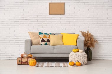 Konforlu kanepe, vazoda otlar, balkabakları ve bavulla dolu bir vazo sonbahar salonunda oturma odası.