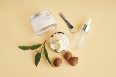 Kavanozlar dolusu fıstık ve bej arka planda kozmetik damlası şişesi.