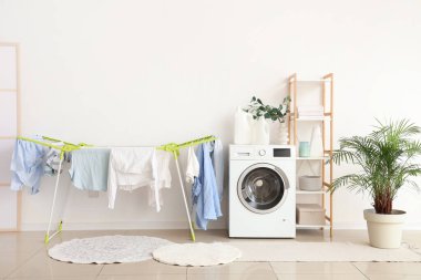 Modern çamaşır makinesi, raf ünitesi ve asma kurutuculu ev çamaşırhanesi.