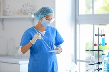 Profesyonel cam takımlı genç bir bilim adamı araştırma laboratuarında su kalitesini inceliyor.