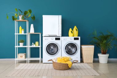 Çamaşır makinesi, kurutma makinesi ve sepetleri olan bir çamaşırhane.