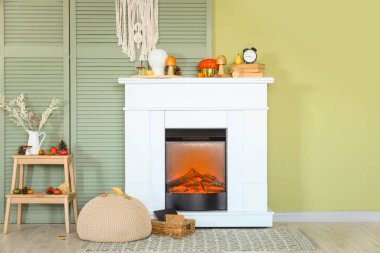 Şöminesi, kahve masası, çalar saati ve balkabağı olan modern oturma odası. Sonbahar konsepti