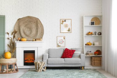 Şömineli şık bir oturma odası, rahat bir kanepe, sehpa ve balkabağı. Sonbahar konsepti