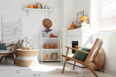 Beyaz şömineli, koltuklu, sehpalı ve balkabaklı rahat bir oturma odası. Sonbahar konsepti