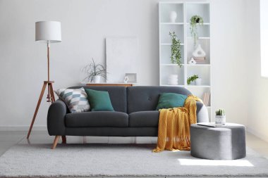 Oturma odasının içinde rahat bir kanepe, puf ve zemin lambası.