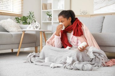 Evde hapşıran peçeteli ve haplı Afro-Amerikalı kız.