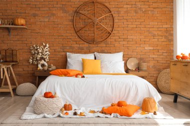 Büyük yataklı, balkabaklı ve sonbahar dekorlu rahat bir yatak odası.