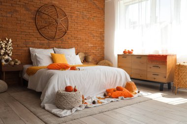 Büyük yataklı, balkabaklı ve sonbahar dekorlu rahat bir yatak odası.