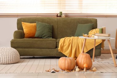 Kanepesi, masası ve sonbahar dekoru olan rahat bir oturma odası.