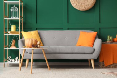 Kanepesi, raf ünitesi ve sonbahar dekoru olan rahat bir oturma odası.