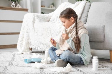 Hasta küçük kız termometreyle evde yere düşüyor.