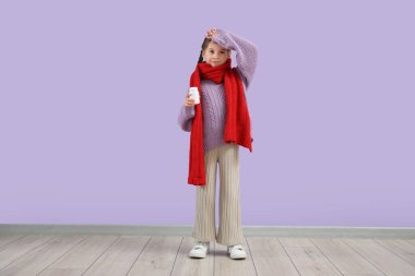 Leylak arka planında fular ve ilaç şişesi olan hasta küçük bir kız.