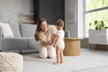 Mutlu anne bebeğiyle evde yürümeyi öğreniyor.