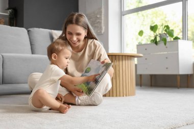 Anne evde bebeğine kitap okuyor.