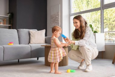 Sevimli bebek, oyuncaklarla yürümeyi öğreniyor ve annesi evde.